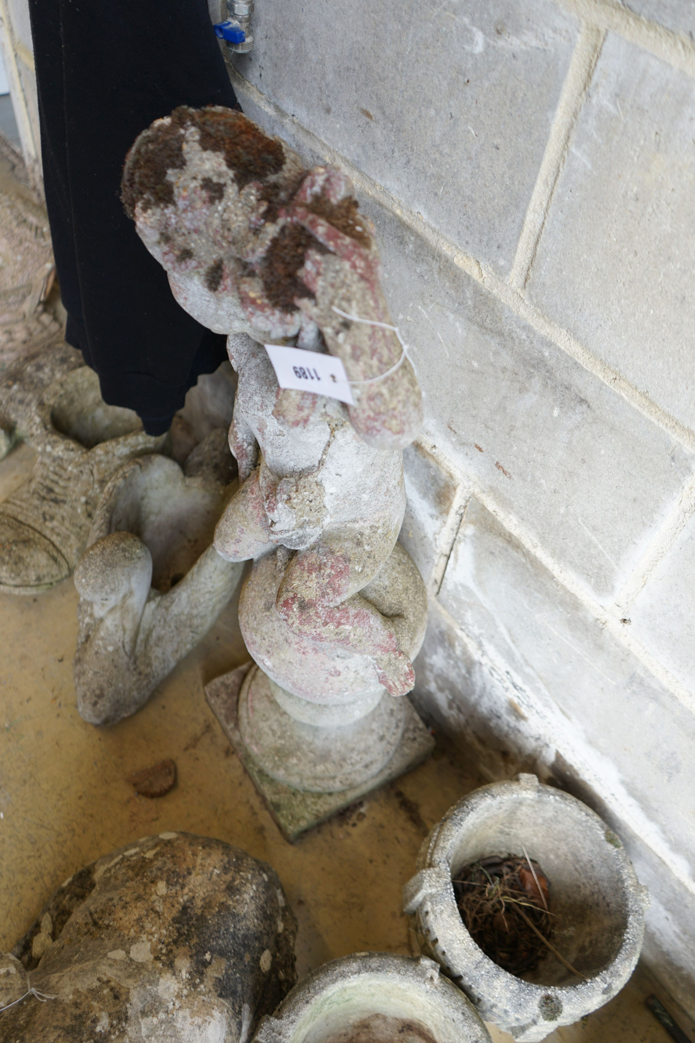 A reconstituted stone seated cherub and orb garden ornament, height 84cm